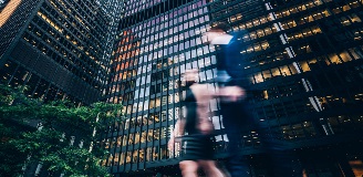 Two people walking around a skyscraper