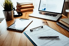 A table of contract on a clipboard with a laptop